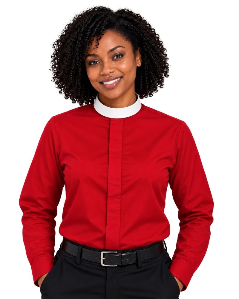 A smiling woman with curly black hair wearing a long-sleeve red clerical shirt with a white collar, paired with black trousers and a black belt, against a plain white background.