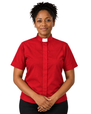 A woman wearing a short-sleeve red clerical shirt with a white collar, paired with black trousers, standing against a plain white background.
