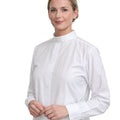 A woman wearing a white long-sleeve clerical shirt with a high mock neck collar, photographed against a solid white background.