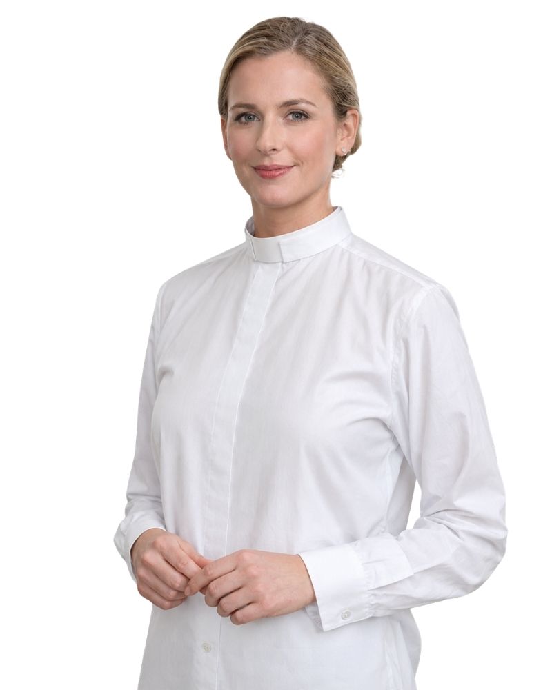 A woman wearing a white long-sleeve clerical shirt with a high mock neck collar, photographed against a solid white background.