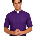 A man wearing a purple short-sleeve clerical shirt with a white collar, paired with a black belt and black trousers, photographed against a solid white background.