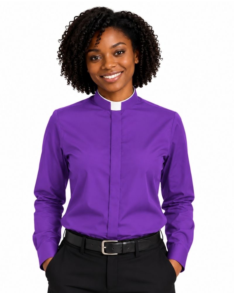 A smiling woman with curly black hair wearing a purple long-sleeve clerical shirt with a white collar, paired with black trousers and a black belt, against a plain white background.