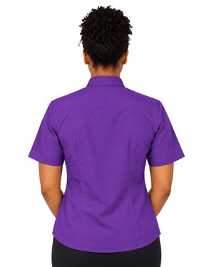 A woman viewed from the back wearing a short-sleeve purple clerical shirt and black pants, set against a plain white background.