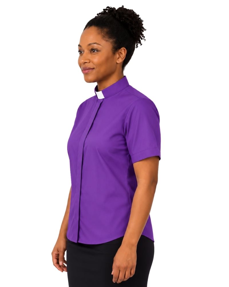A woman wearing a purple short-sleeve clerical shirt with a white collar tab, shown in profile against a plain white background.