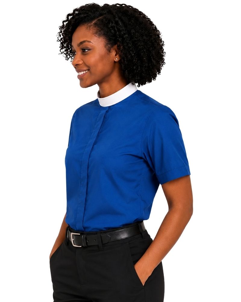 A woman wearing a royal blue short-sleeve clerical shirt with a contrasting white collar, paired with black trousers and a black belt, shown from a side profile against a plain white background.