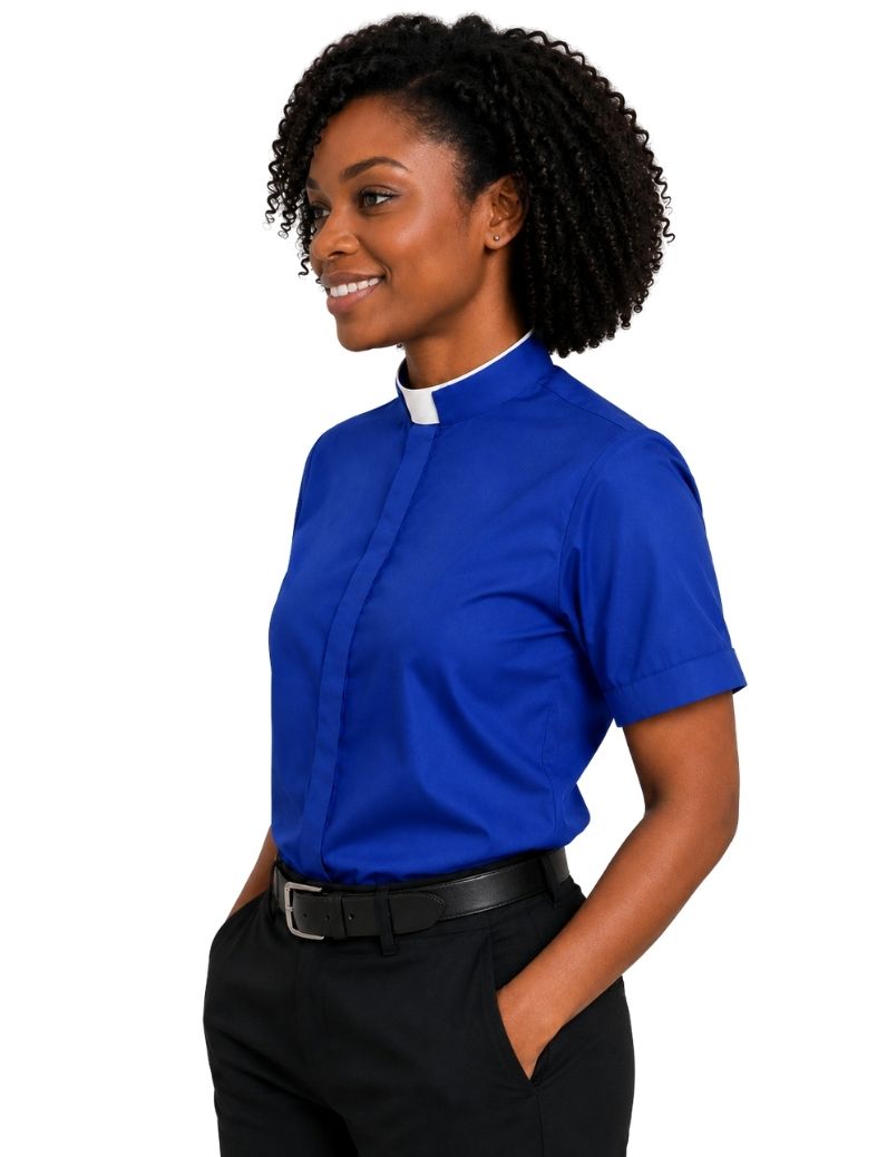 A woman wearing a royal blue short-sleeve clerical shirt with a white collar, paired with black trousers and a black belt, shown from the waist up against a plain white background.