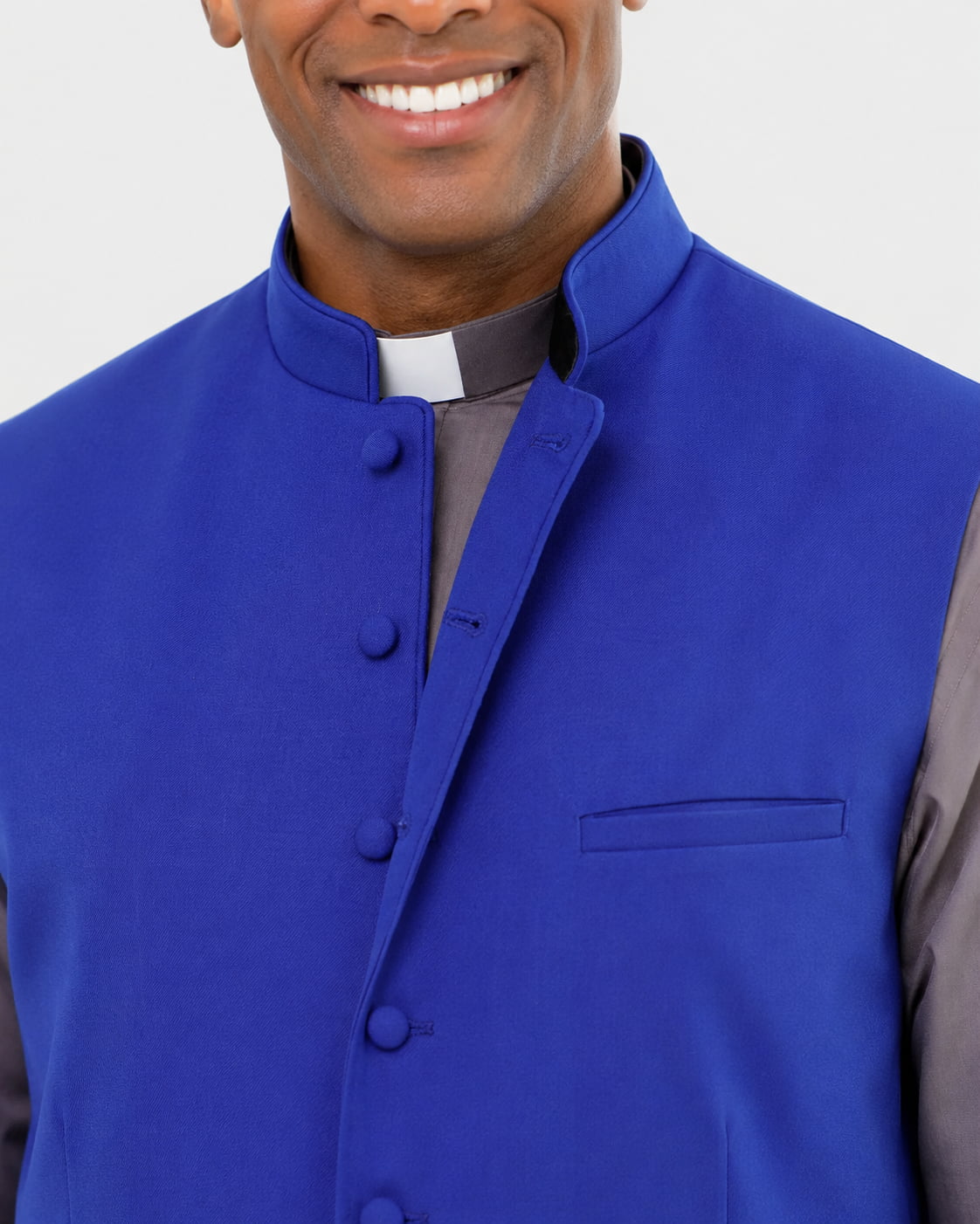 Man wearing a blue vest over a gray shirt with a white collar.