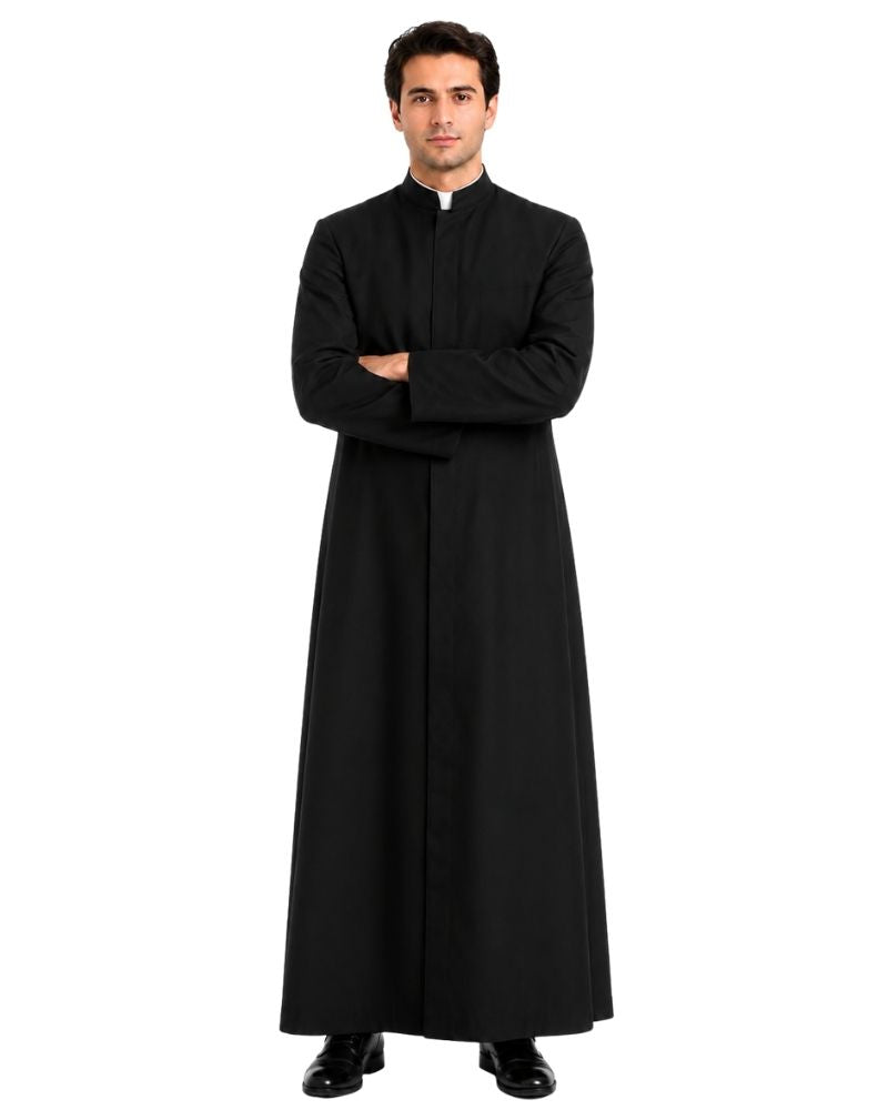 A man modeling a long black clerical robe with a white collar, standing with arms crossed against a plain white background.