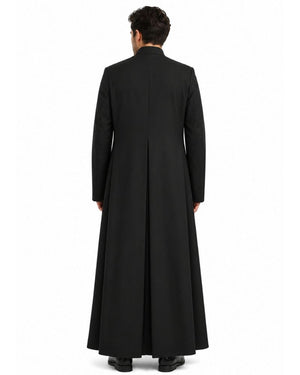 A man viewed from the back wearing a long black robe with a high collar and long sleeves, standing against a plain white studio background.