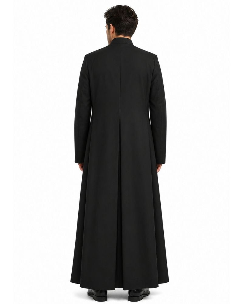 A man viewed from the back wearing a long black robe with a high collar and long sleeves, standing against a plain white studio background.