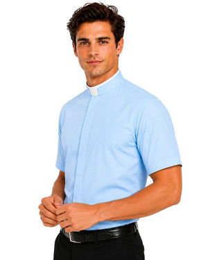 A man wearing a light blue short-sleeve clerical shirt with a white clerical collar, paired with black trousers and a black belt, against a plain white background.