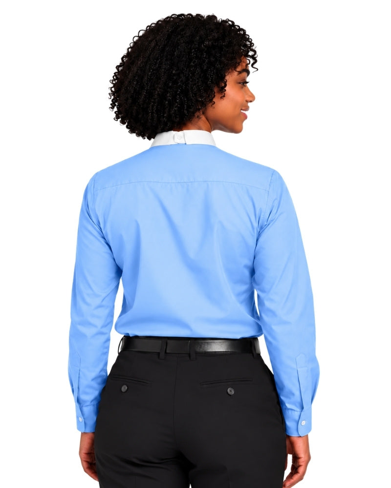 A woman with curly black hair is shown from the back wearing a light blue long-sleeve clerical shirt tucked into black trousers with a black belt, against a plain white background.