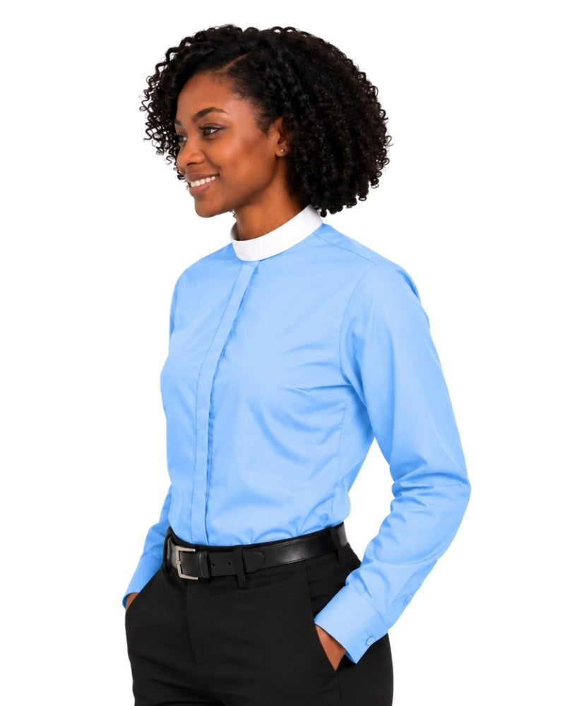 A woman with curly black hair wearing a light blue long-sleeve clerical shirt with a white collar, paired with black trousers and a black belt, shown from a side profile against a white background.