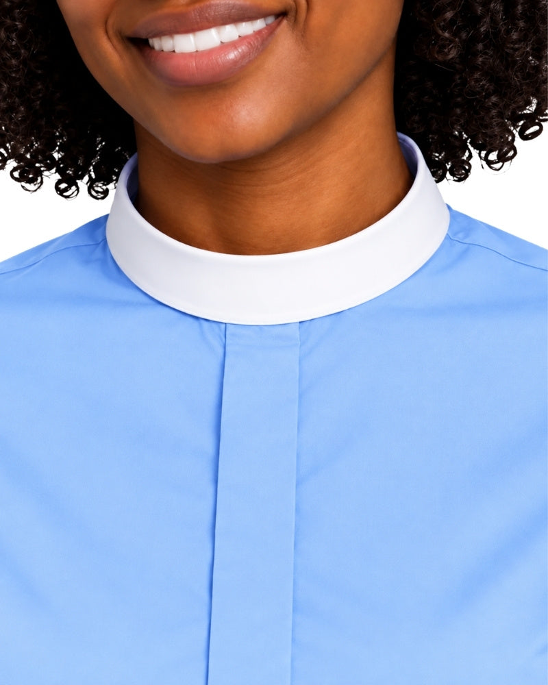 Close-up of a woman wearing a light blue clerical shirt with a contrasting white high stand collar, cropped from the mouth down against a plain white background.