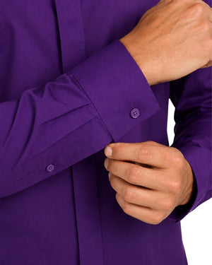 Close-up of a man wearing a solid purple long-sleeve clerical shirt, adjusting the cuff with one hand while the other hand rests near the pocket.