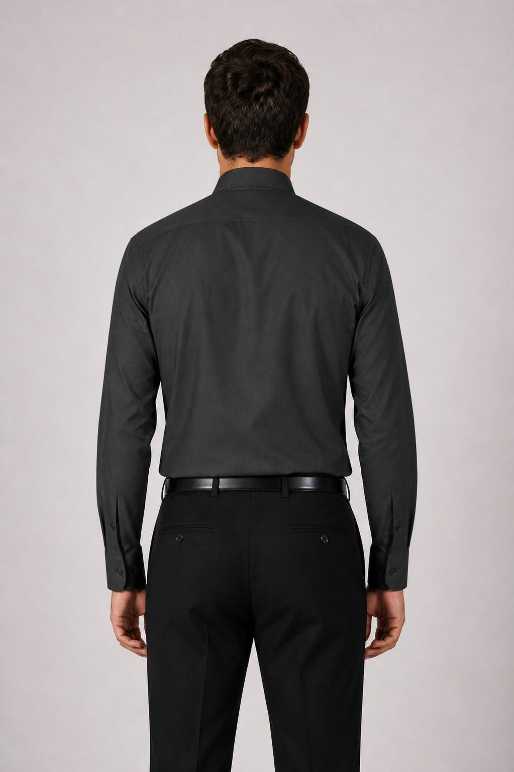 Man wearing a black dress shirt and pants on a light gray background