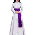 A woman modeling a White Clerical Cassock With Purple Trim with a wide purple waist sash, purple trim details, and a matching purple fringed drape, set against a plain white background.
