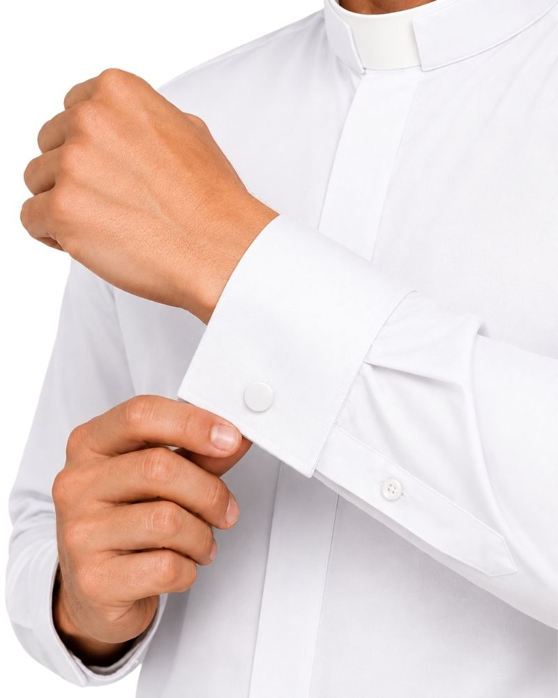 A close-up of a man wearing a white long-sleeve clerical shirt with a white collar and adjusting the cuff with one hand while wearing the other hand near the cuff.