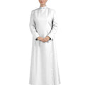 A woman modeling a long white  robe with long sleeves and black shoes, photographed against a plain white background.