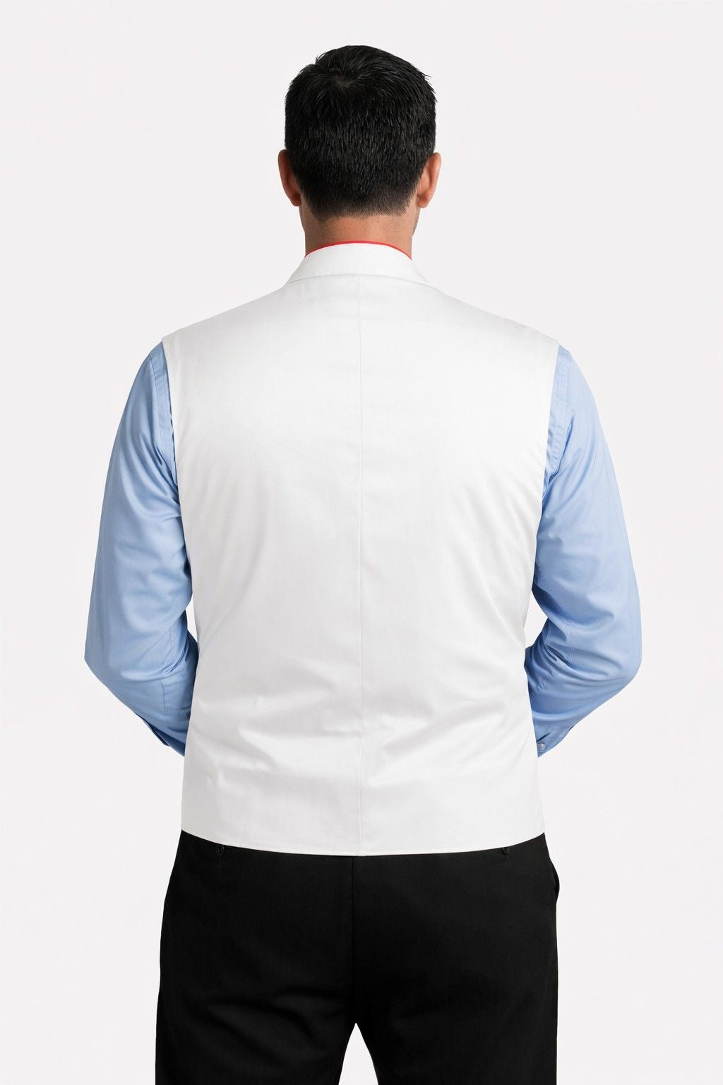 Man wearing a white vest over a blue shirt with a plain background