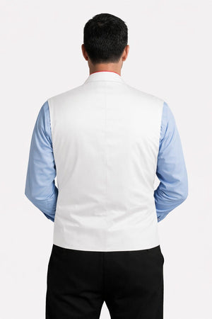 Man wearing a white vest over a blue shirt with a plain background