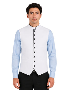Man wearing a light blue dress shirt white vest with black buttons on a white background.