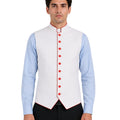Man wearing a light blue clerical shirt white vest with orange buttons on a white background.