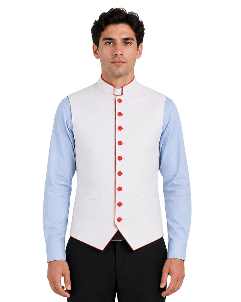 Man wearing a light blue clerical shirt white vest with orange buttons on a white background.