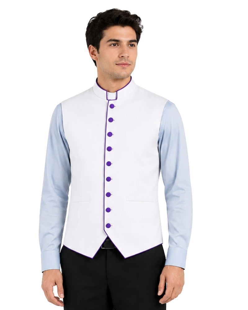 Man wearing a light blue clerical shirt white vest with purple buttons on a white background.