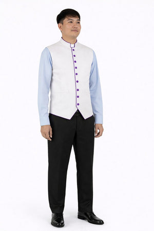 Man wearing a light blue dress shirt, white vest with purple buttons, black pants, and black shoes on a white background