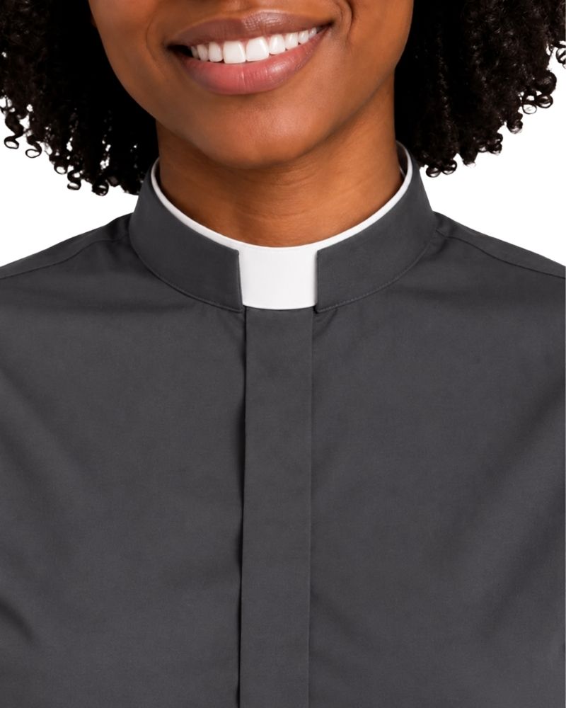 A close-up of a woman wearing a dark charcoal gray clerical shirt with a white collar, showing the collar and upper chest against a plain white background.