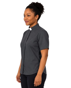 A woman wearing a dark gray short-sleeve clerical shirt with a white clerical collar, shown in profile against a plain white background.