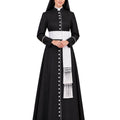 A woman modeling a  Black Clergy Cassock with a white waistband, white vertical button placket, and a white sash with fringe, photographed against a plain white background.