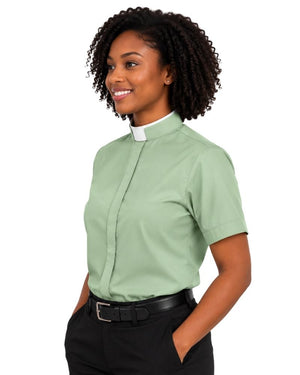 A woman wearing a light sage green short-sleeve clerical shirt with a white collar, paired with black trousers and a black belt, shown against a plain white background.