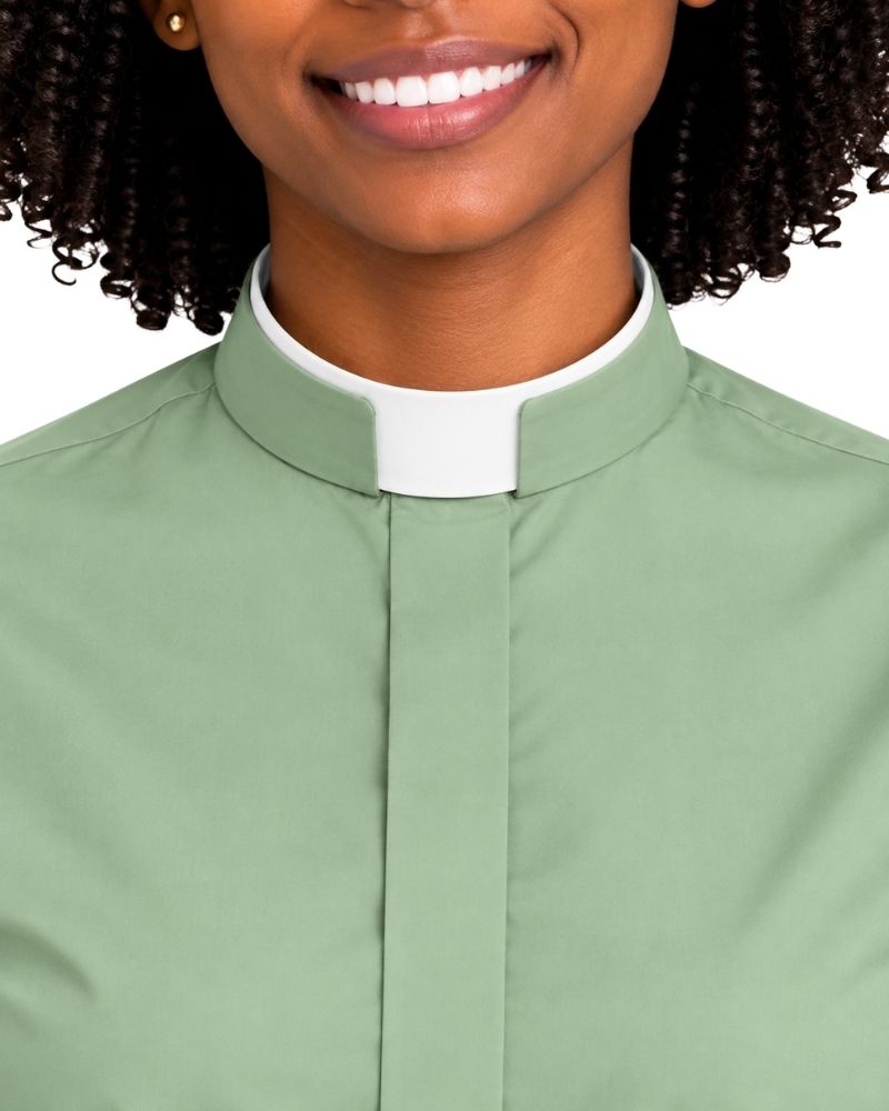 A close-up of a woman wearing a sage green clerical shirt with a white collar, set against a plain white background.