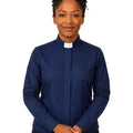 A woman wearing a navy blue long-sleeve clerical shirt with a white collar, standing against a plain white background.