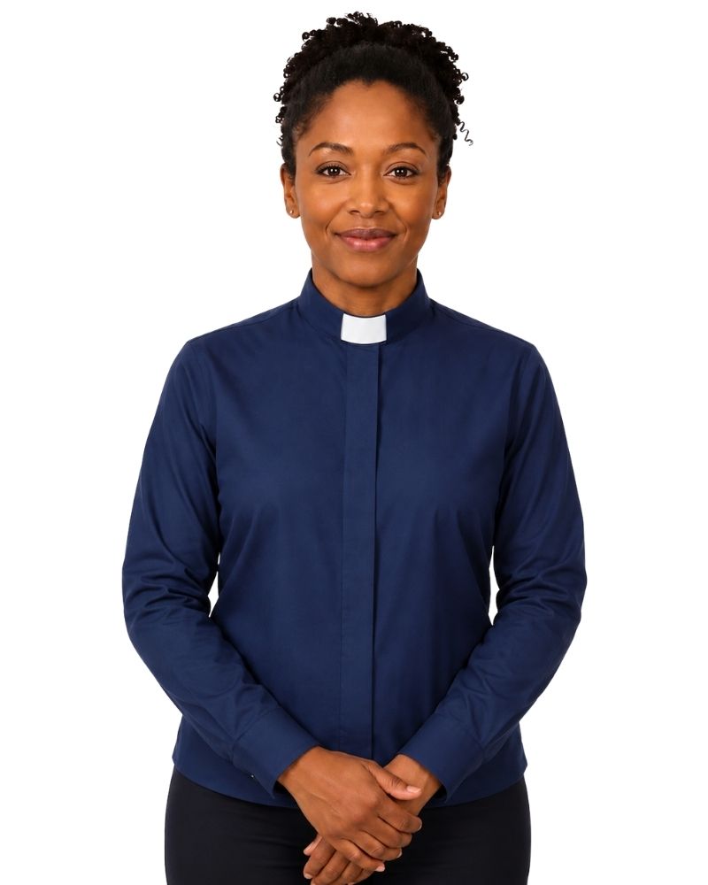 A woman wearing a navy blue long-sleeve clerical shirt with a white collar, standing against a plain white background.