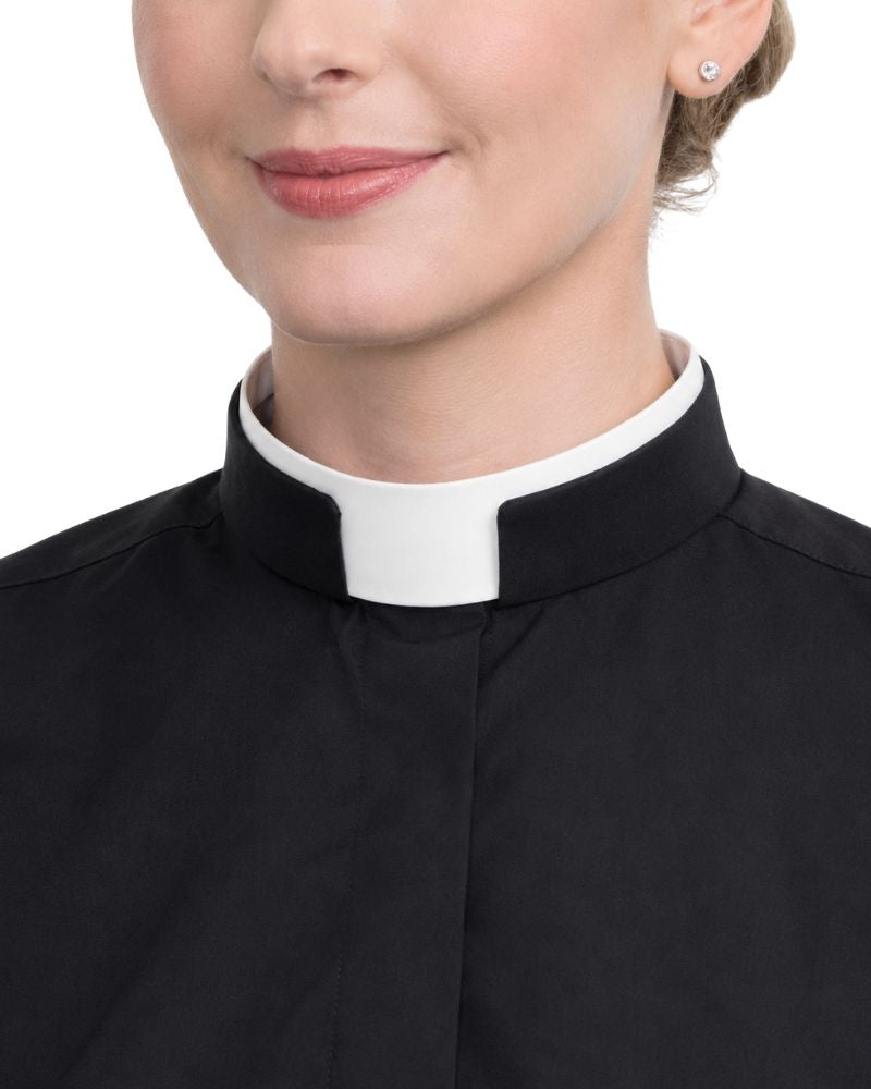 A close-up of a women wearing a black clerical-style collar with a white tab, likely a priest or minister collar, against a plain white background.