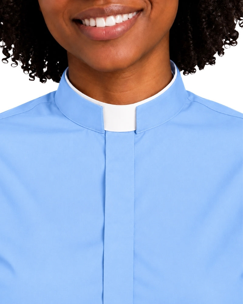 A close-up of a woman wearing a light blue clerical shirt with a white collar tab, shown against a plain white background.