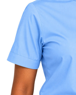 Close-up of a woman wearing a light blue short-sleeve clerical shirt, showing the sleeve cuff and shoulder area against a plain white background.