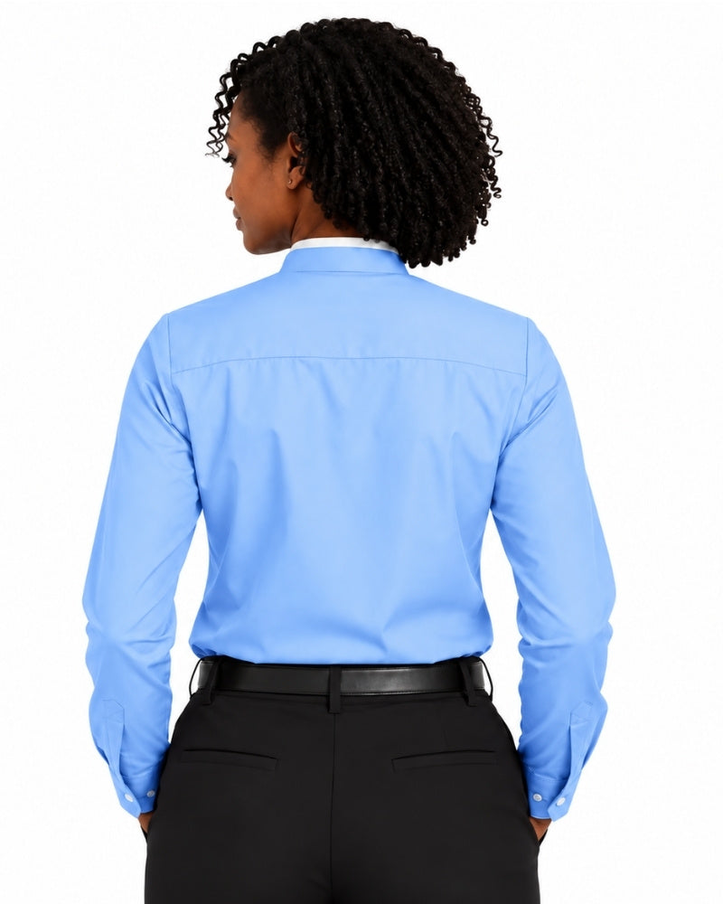 A woman shown from the back wearing a light blue long-sleeve clerical shirt tucked into black trousers with a black belt, against a plain white background.