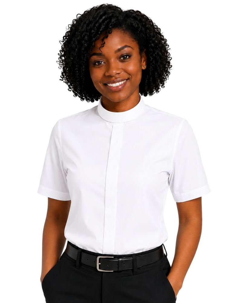 A smiling woman with curly black hair wearing a white short-sleeve clerical shirt, paired with black trousers and a black belt, against a plain white background.