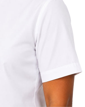 Close-up of a women wearing a plain white short-sleeve clerical shirt, showing the sleeve and part of the arm against a light neutral background.