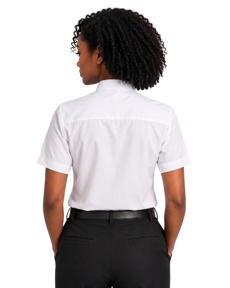 A woman with curly black hair is shown from the back wearing a white short-sleeve clerical shirt and black trousers against a plain white background.