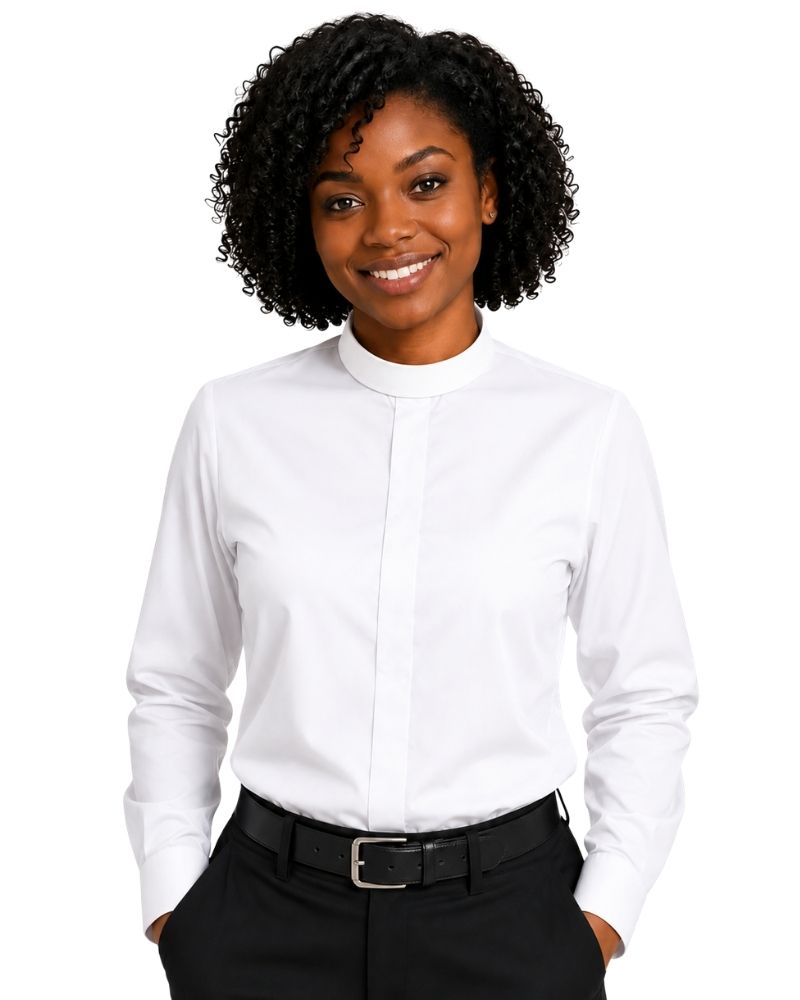 A woman with curly black hair wearing a white long-sleeve clerical shirt with a mock neck, paired with black trousers and a black belt, against a plain white background.