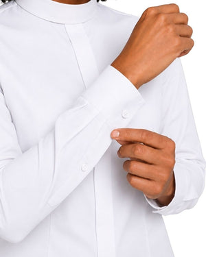 A close-up of a women wearing a white long-sleeve clerical shirt, adjusting the cuff with one hand while the other hand rests near the front button.