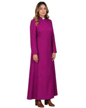 A woman wearing long magenta robe with a high mock neck, long sleeves, and a small button closure at the chest, paired with brown leather boots against a white background.