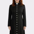 Woman wearing a black long coat with silver buttons on a white background