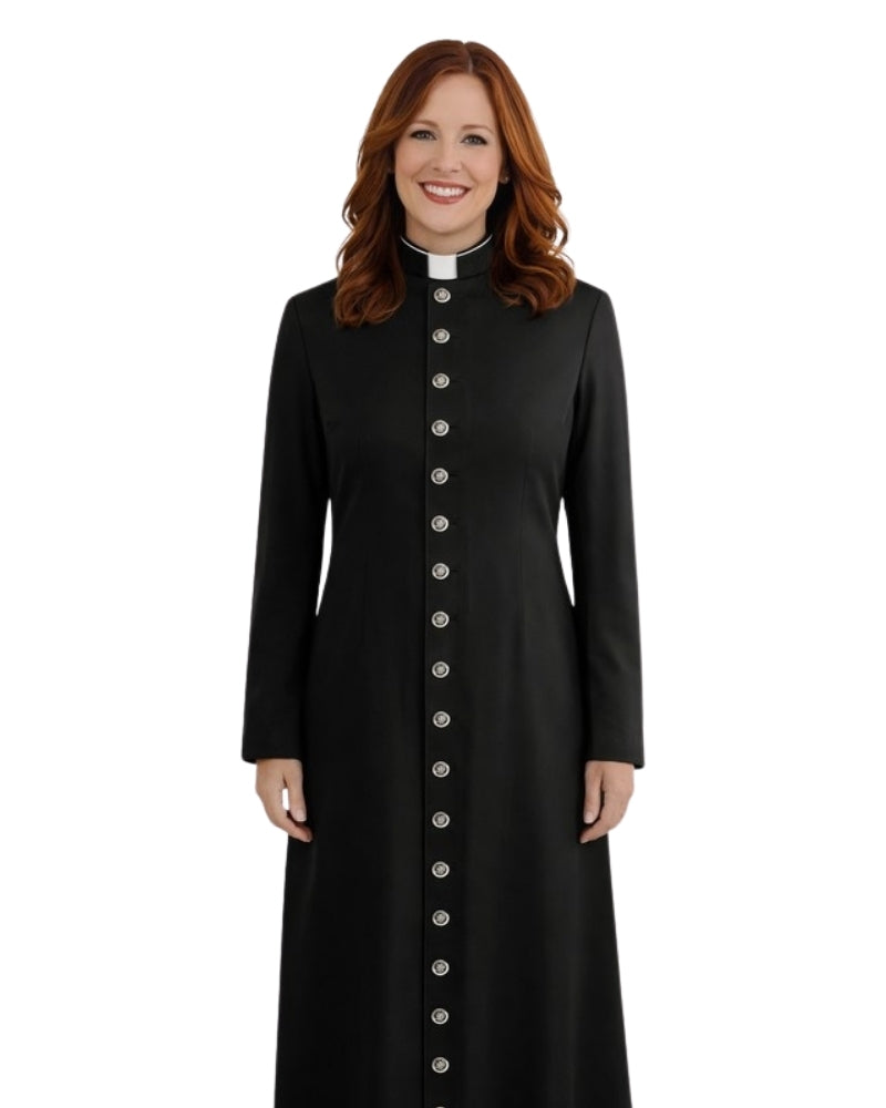 A smiling woman with red hair wearing a long black cassock with a white collar and a vertical row of silver buttons down the front, photographed against a plain white background.