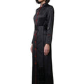 Woman wearing a long black dress with red buttons on a white background